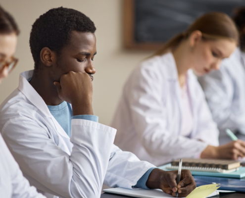 Grupo de estudantes de medicina sentados numa mesa estudando durante um programa complementar de fellow