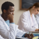 Grupo de estudantes de medicina sentados numa mesa estudando durante um programa complementar de fellow