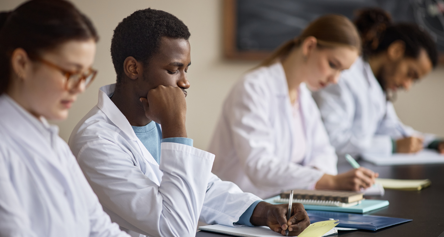 Grupo de estudantes de medicina sentados numa mesa estudando durante um programa complementar de fellow